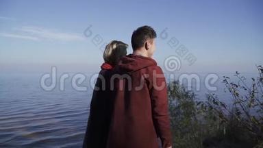 年轻夫妇站在水面的背景上。 一对情侣在户外约会。 年轻人的关系